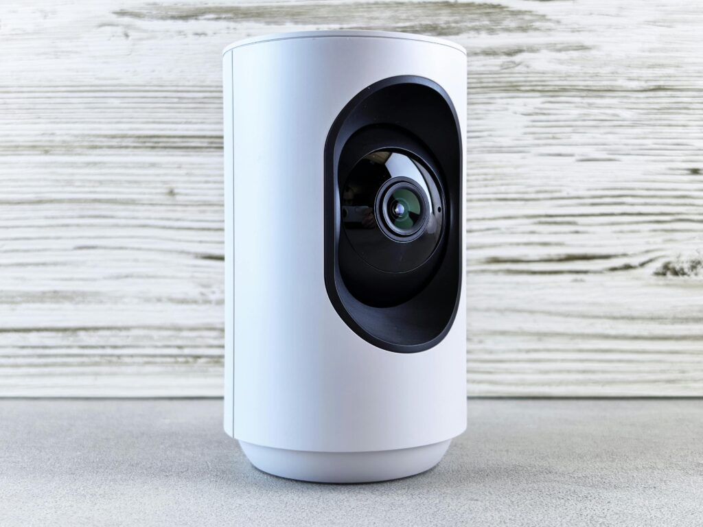 Close-up of a white indoor security camera against a wooden backdrop, showcasing modern design.